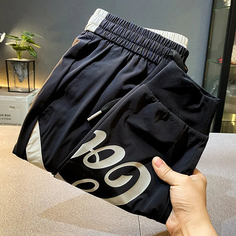 Men's solid black cotton trousers with elasticated ankle bands, shown in a casual style.