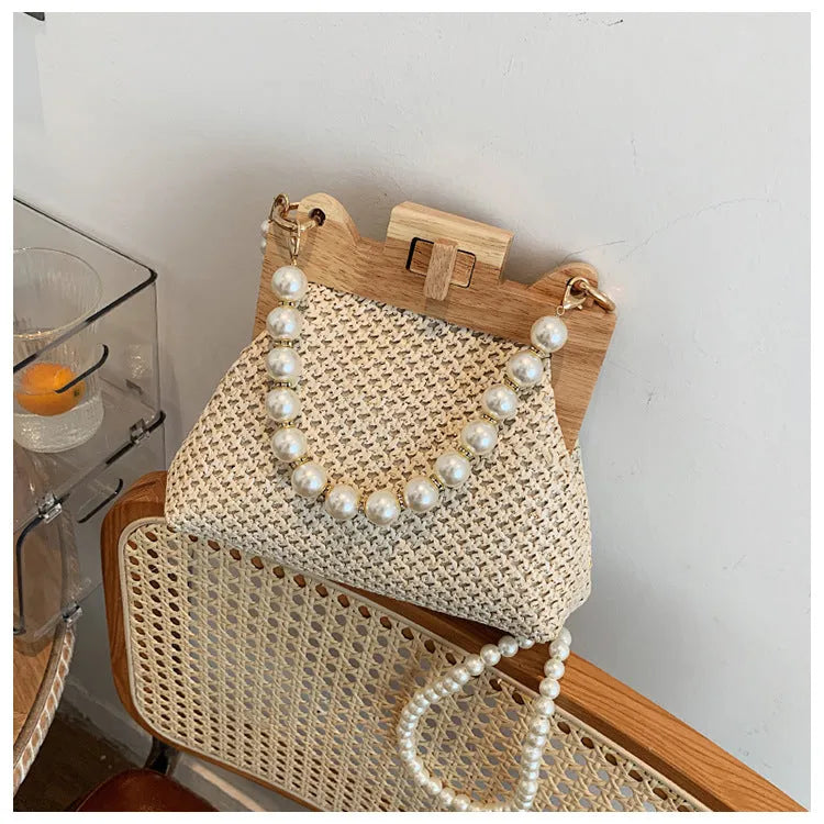 Beige woven straw women's shoulder bag with pearl chain detail, showing interior zipper pockets.