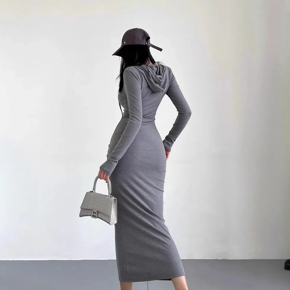A woman wearing a grey high-waist hooded long sleeve sheath dress, knee-length pullover style.