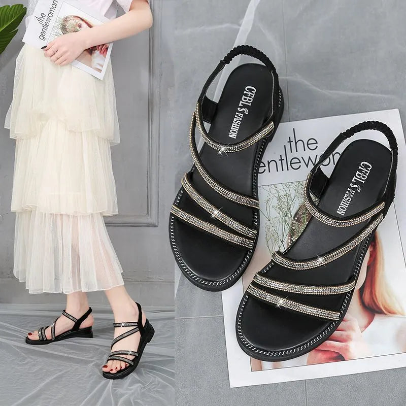 Women's silver flat sandals with rhinestone decoration and elastic band, shown on a white background.