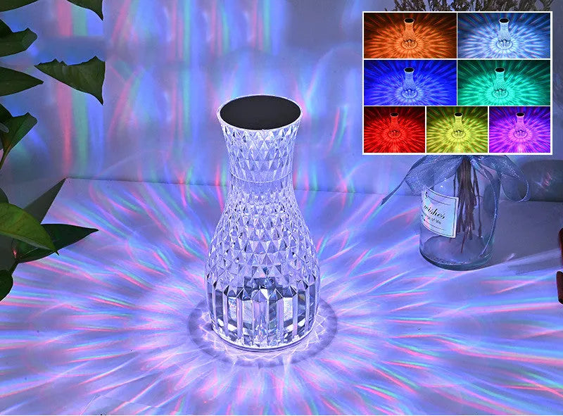 Clear plastic vase-shaped crystal bedside lamp with LED lights on a wooden table.