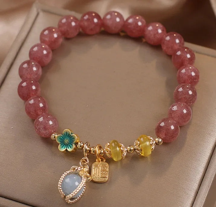 Red women's beaded bracelet made with natural strawberry quartz stones, alloy spacers, and rhinestone accents.