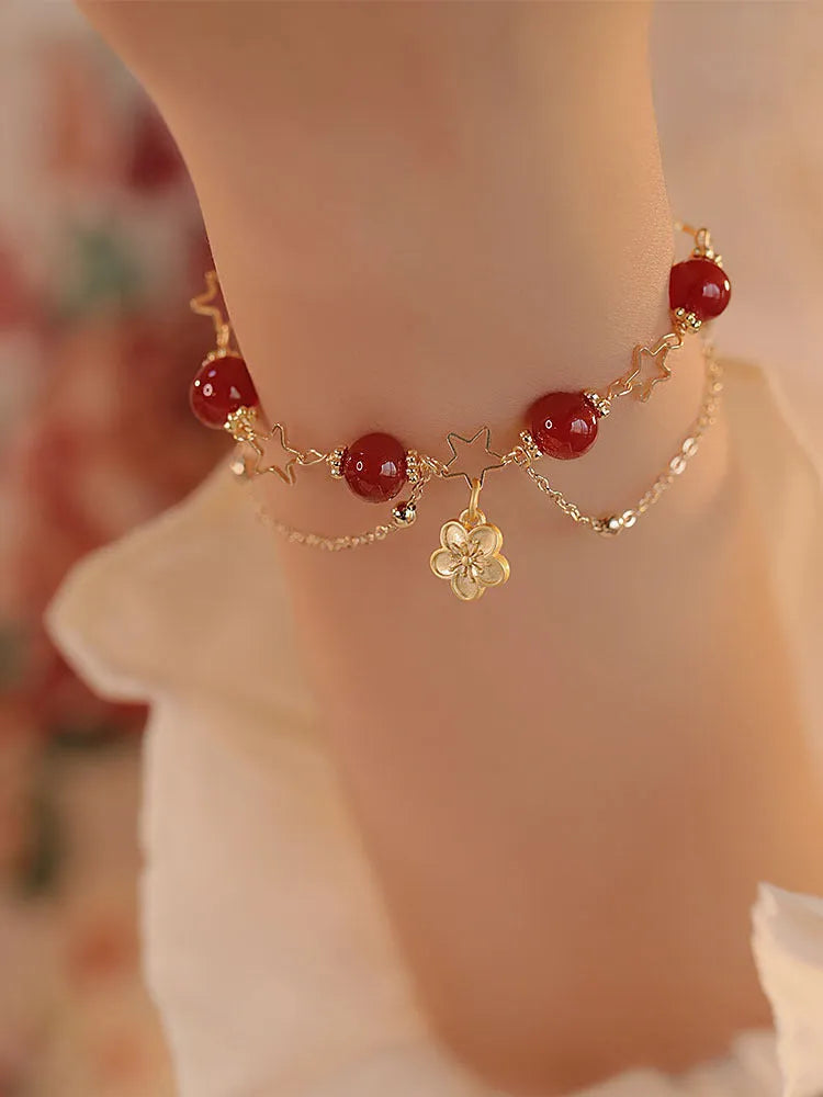 Red agate double layer women's bracelet with peach blossom design on adjustable string.