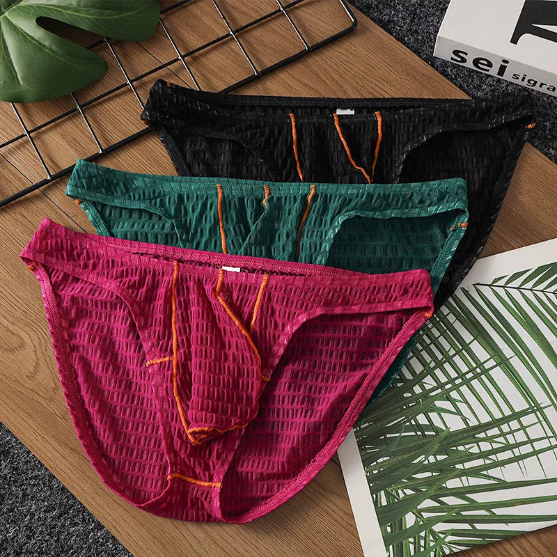 Men's low-waist lace briefs in white, black, green, red, and purple colours laid flat.