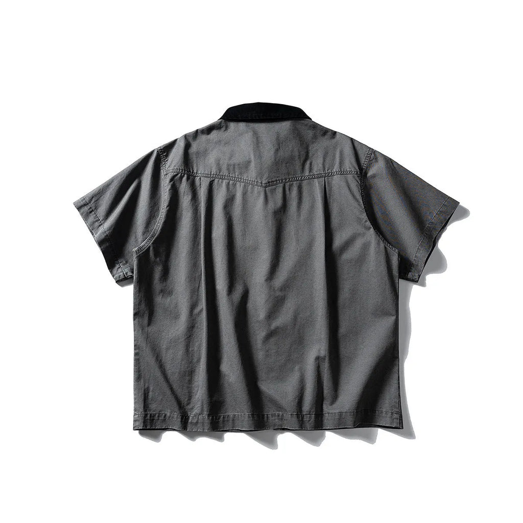 Washed khaki loose-fit cotton overalls shirt with short sleeves on a hanger.