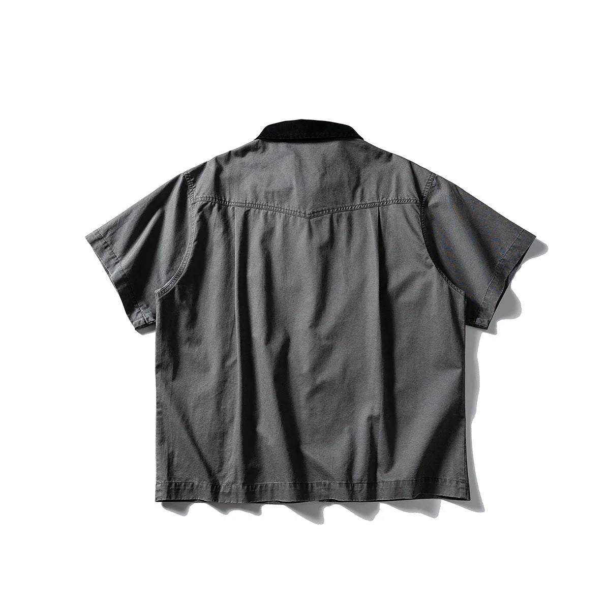 Washed khaki loose-fit cotton overalls shirt with short sleeves on a hanger.