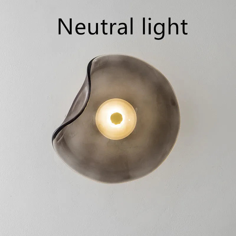 Round glass wall lamp in a choice of colours for bedroom bedside lighting.