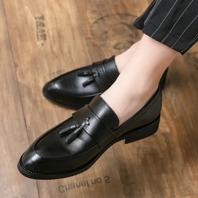 Men's black slip-on business casual shoes with a tassel detail and rubber sole.