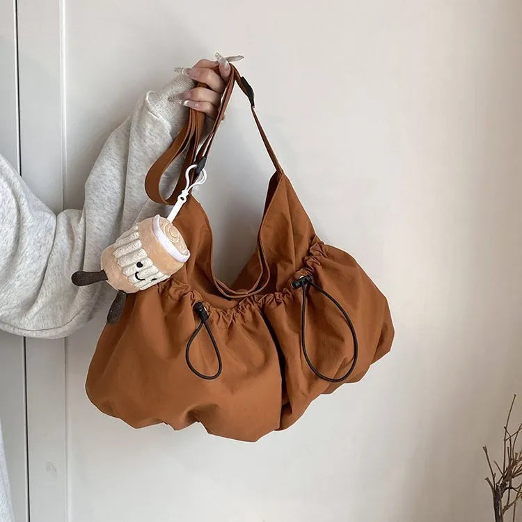 Green ultra-light pleated crossbody student bag showing folding design and split outer pocket