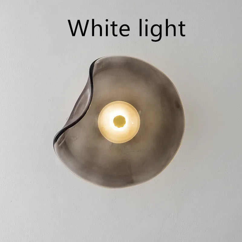 Round glass wall lamp in a choice of colours for bedroom bedside lighting.