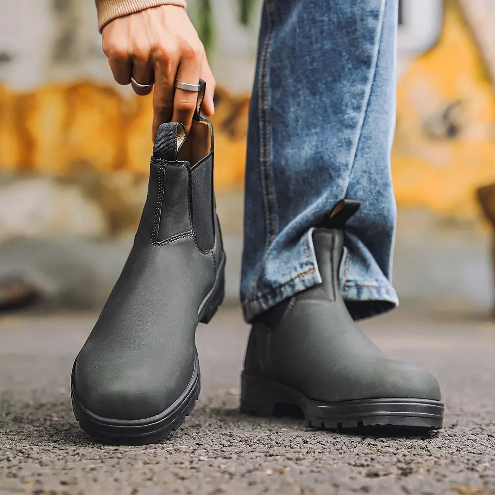 Vintage brown unisex Chelsea boots with a frosted finish, round toe, and low horseshoe heel on a wooden floor.