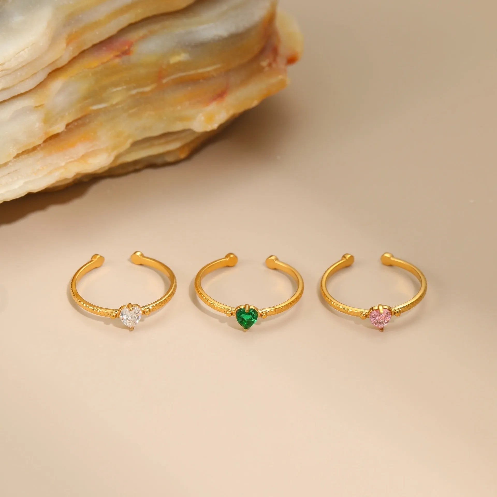 Open ended stainless steel ring with a geometric zircon-inlaid heart in white, pink, or green.