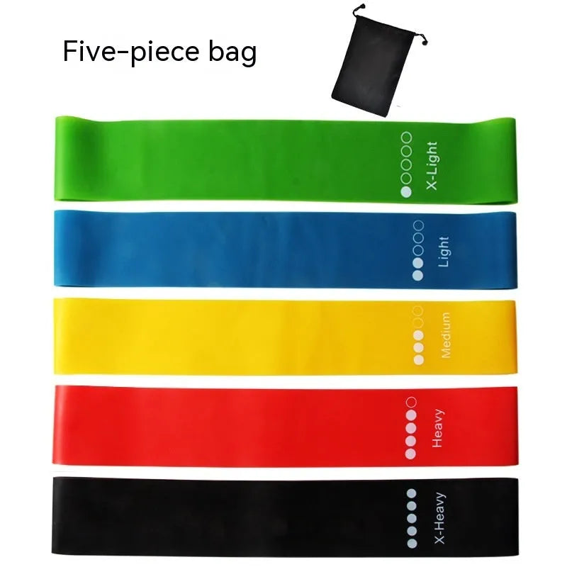 Set of five colour-coded yoga resistance straps in green, blue, yellow, red, and black on a gym mat.
