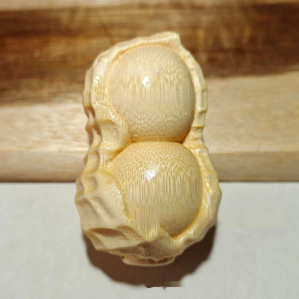 Solid natural bamboo carved peanut ornament with modern simple design on a wooden surface.