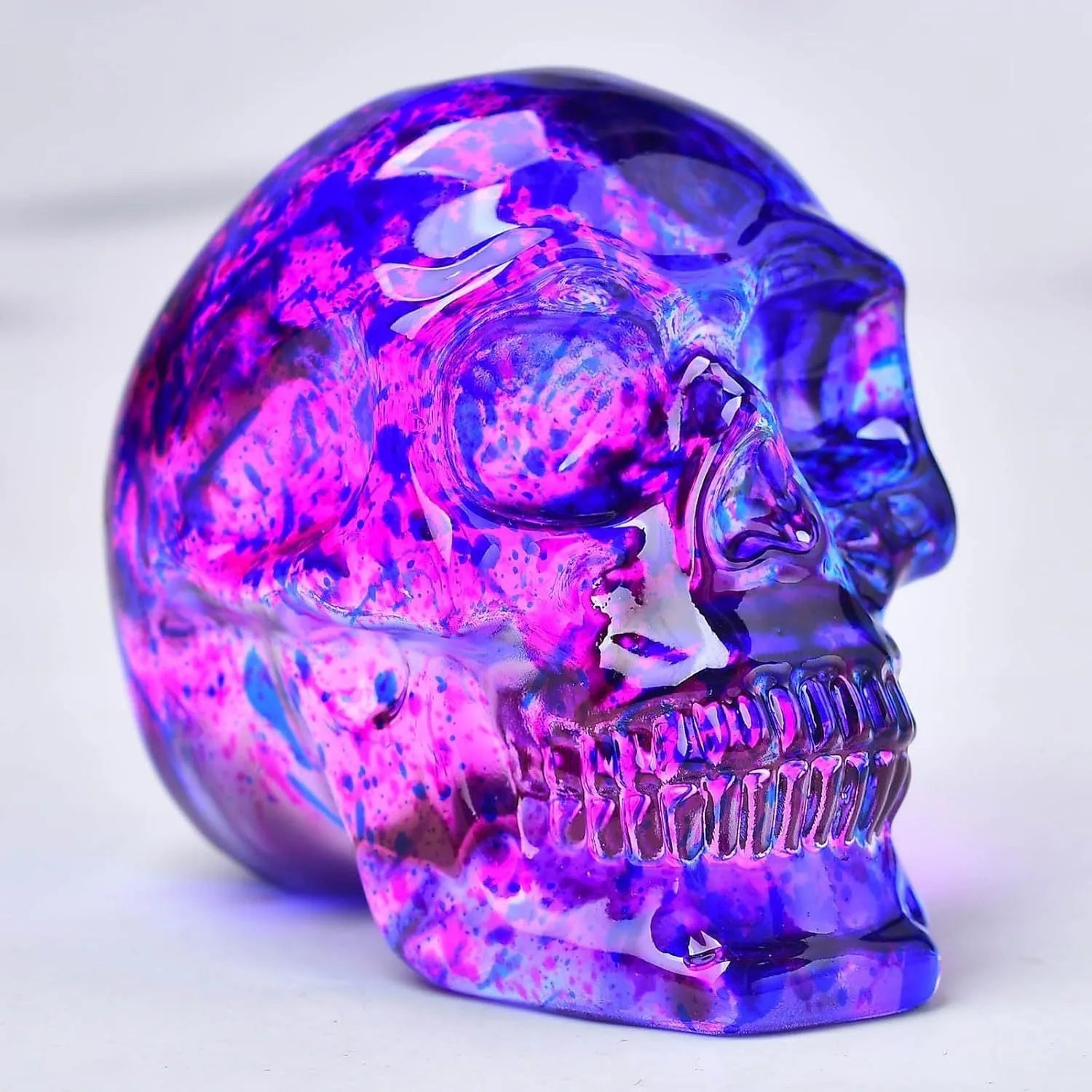 Pink and blue floral glass skull ornament on a shelf for decorative display