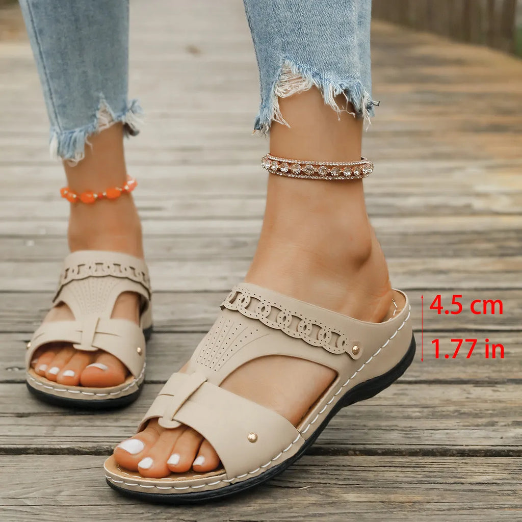 A pair of beige Roman-style slope heel slippers with a fish mouth toe holder on a plain background.