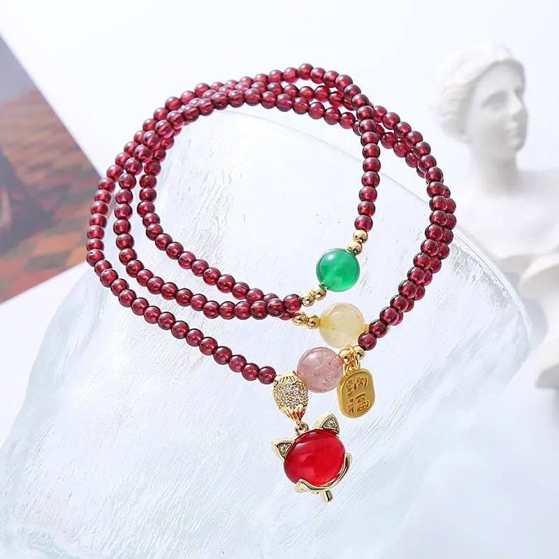 Purplish red rope bracelet with a detailed natural garnet fox pendant and adjustable tie closure.