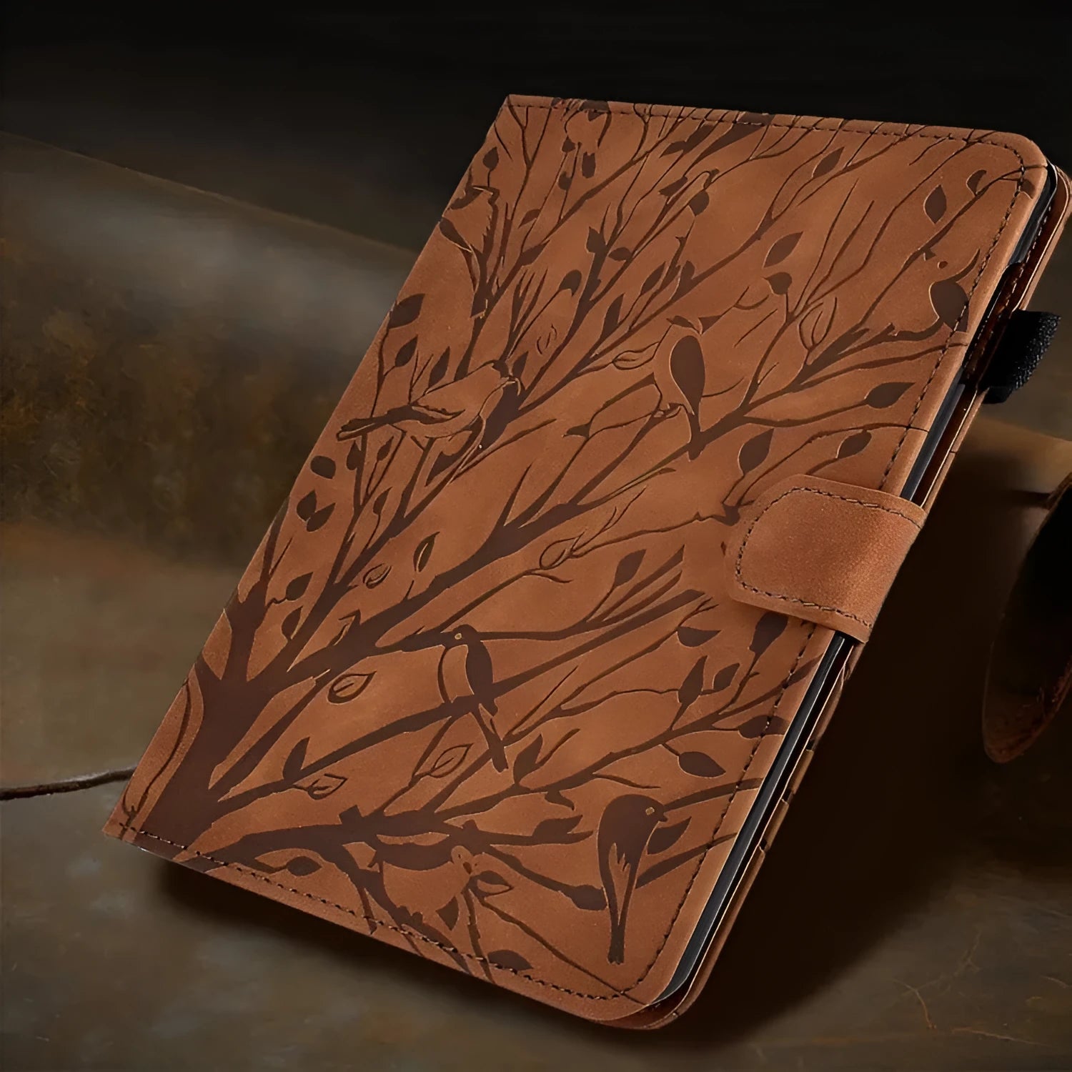 Black imitation leather tablet case with Pachira macrocarpa engraving and built-in viewing bracket open.