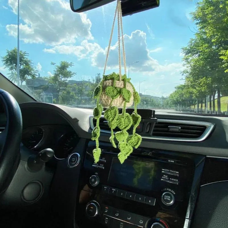 Green and white crochet wool car plant decoration with hanging rope on car dashboard