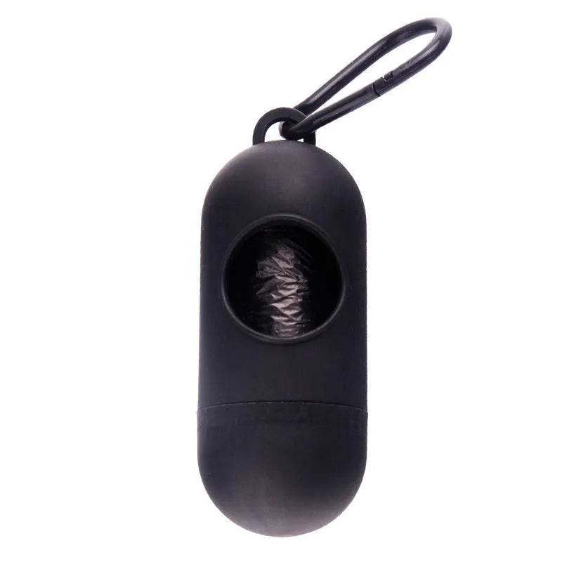 Compact black dog poop bag holder with hook and Velcro strap, shown attached to a pair of trousers.