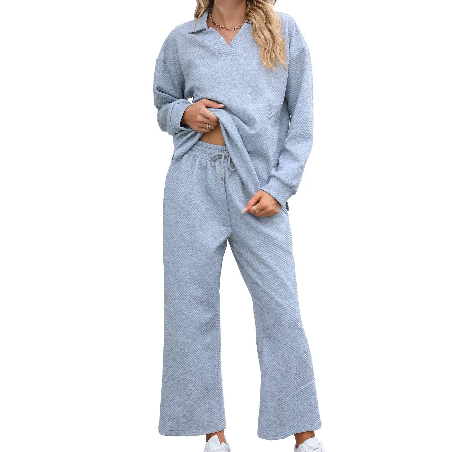 Woman wearing a knitted jacquard long sleeve sweater and matching elastic waist cropped trousers in a solid colour.