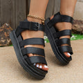 Pair of thick-soled black sandals with an adjustable buckle strap over the instep.
