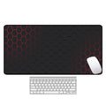 Large black rubber desk mouse pad with a printed geometric pattern, shown on a wooden desk.