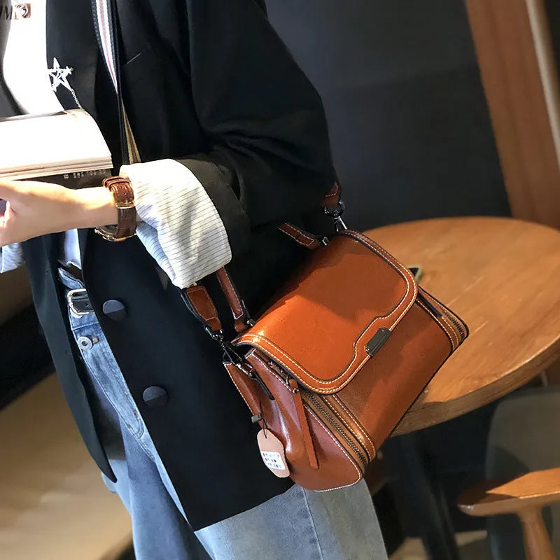 Women's brown genuine oil wax leather messenger bag showing front view with double straps and visible sewing details.