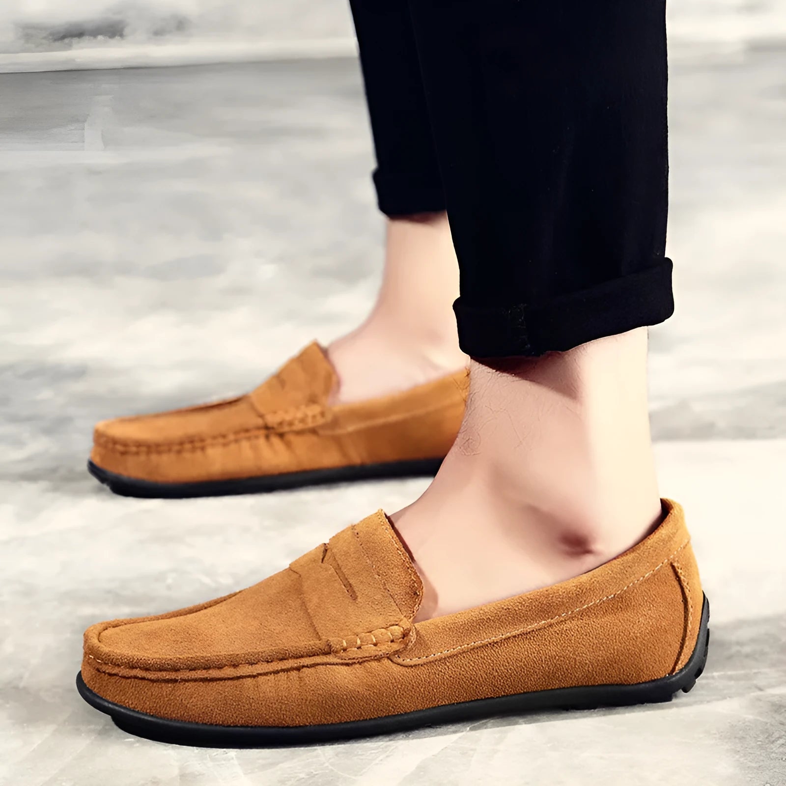 Men's suede slip-on loafers in black on a flat rubber sole, showing round toe and sewing detail.