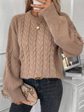Woman wearing a loose beige casual sweater with a twisted texture detail on the front.