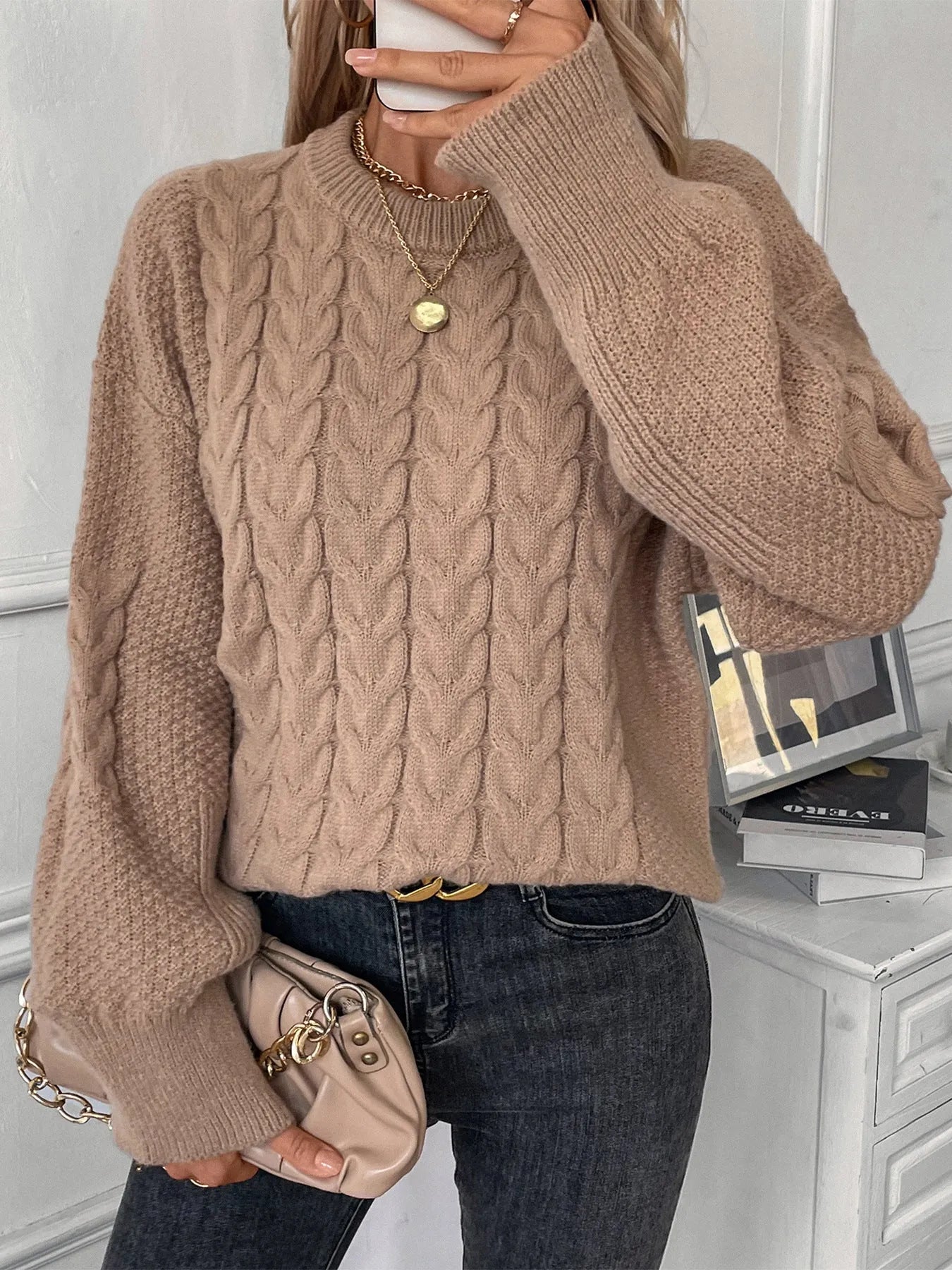 Woman wearing a loose beige casual sweater with a twisted texture detail on the front.