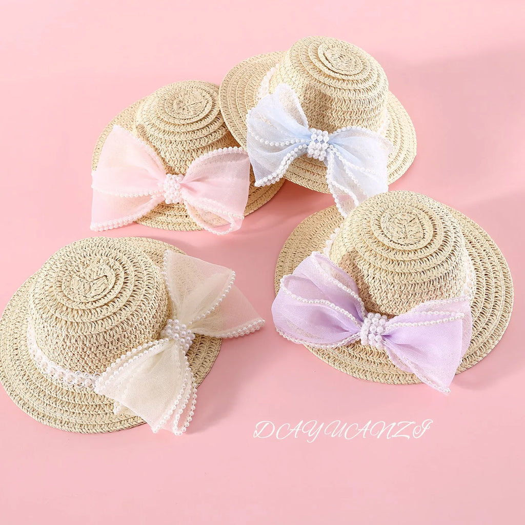 A woven Lafite leaf straw hat for a cat, decorated with a pearl butterfly bow, shown in pink, purple, blue, and white colour options.