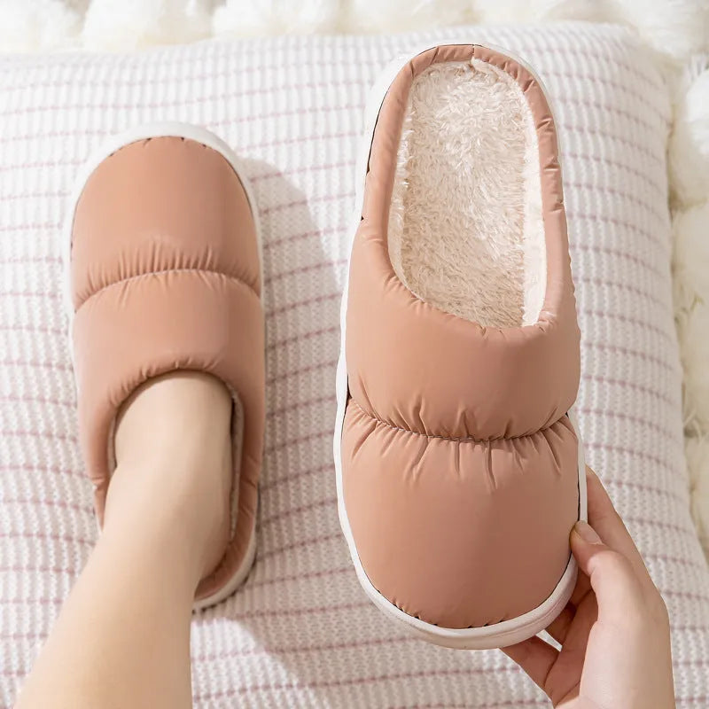 Blue down cotton indoor slippers with thick rubber sole and plush lining on a wooden floor.