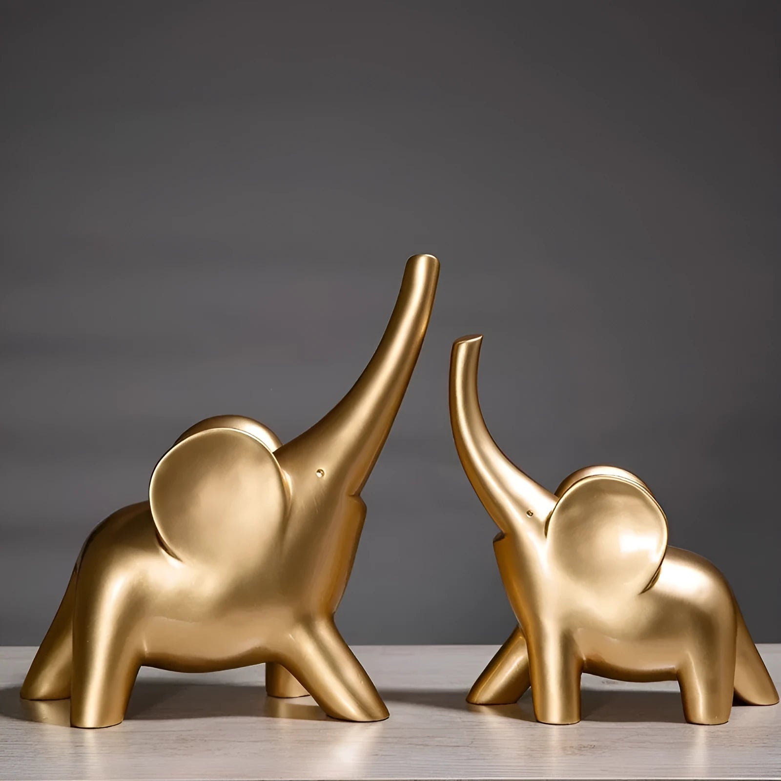 Minimalist rose gold and white resin elephant ornaments on a shelf, showing large and small sizes.