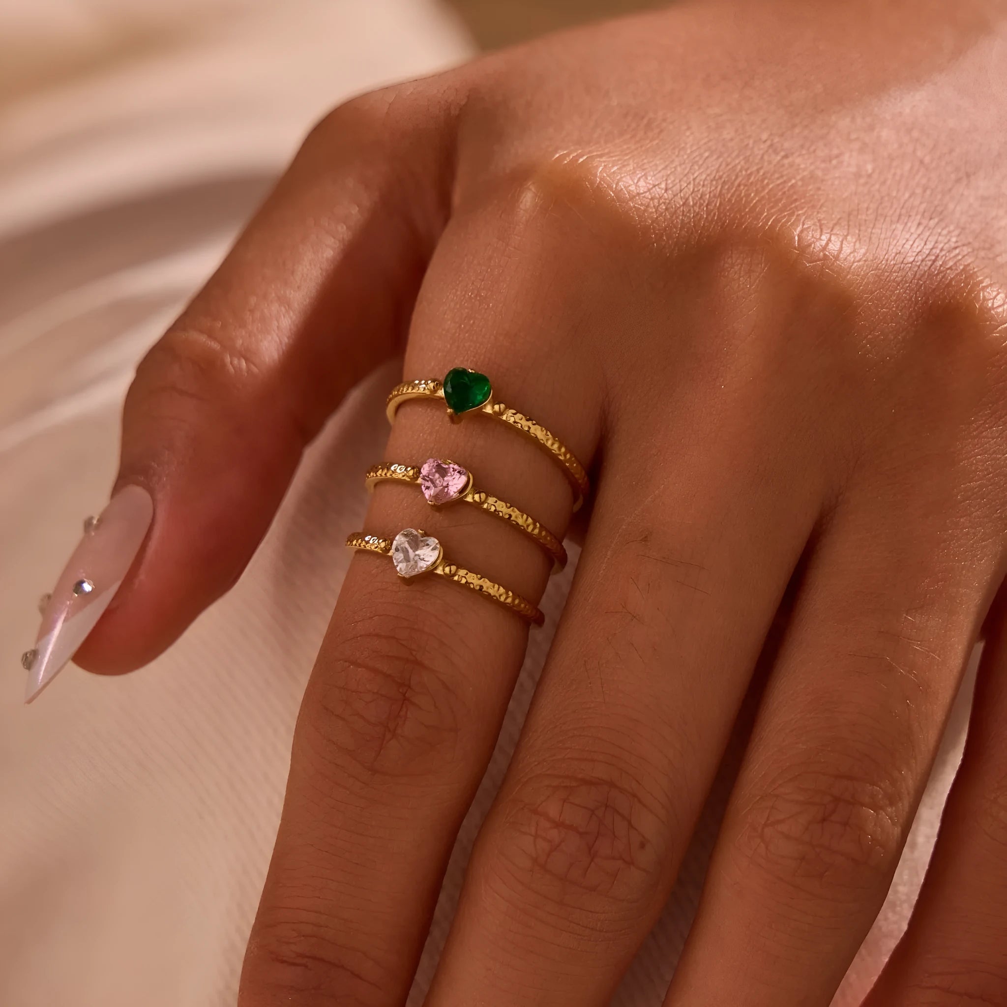 Open ended stainless steel ring with a geometric zircon-inlaid heart in white, pink, or green.