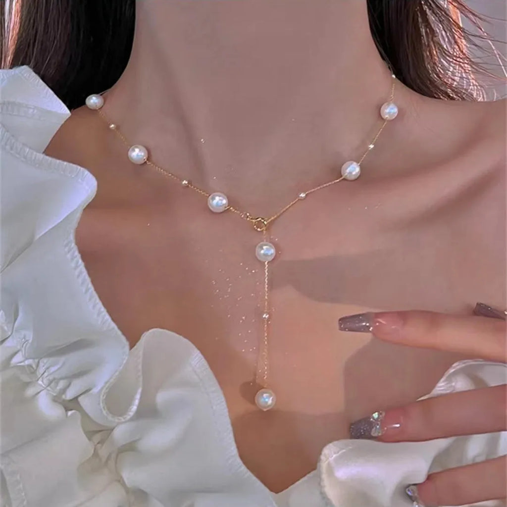 Gold starry pearl choker necklace on a white surface showing imitation pearl chain