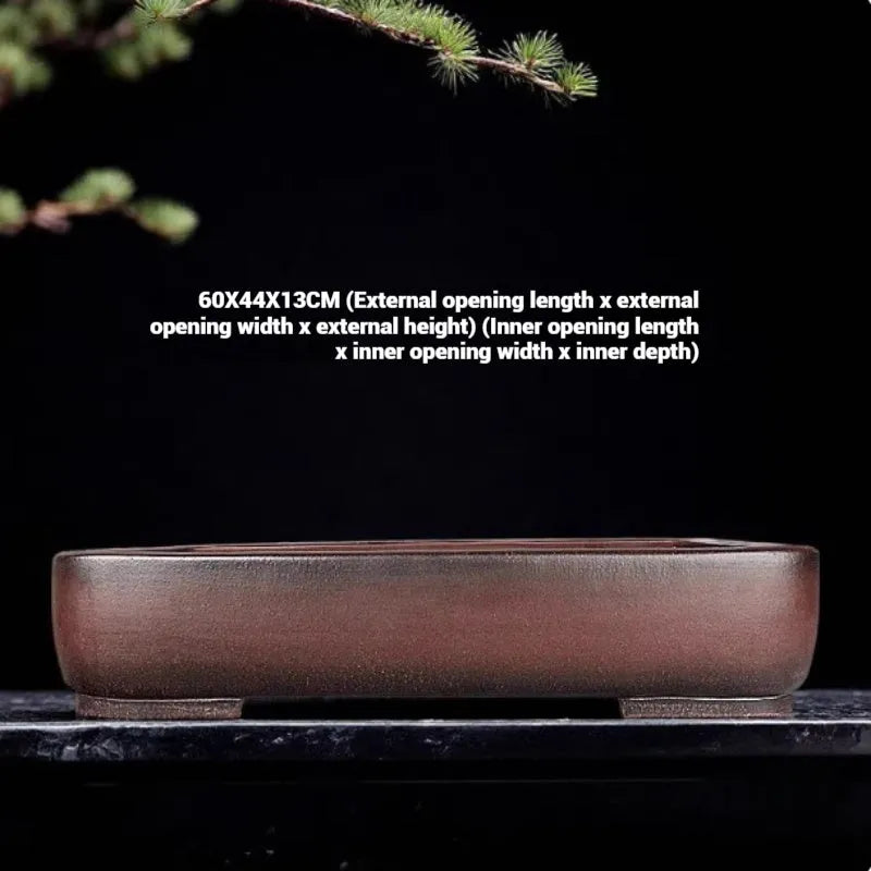 Handmade rectangular purple clay flower pot for indoor plants on a table.
