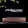 Handmade rectangular purple clay flower pot for indoor plants on a table.