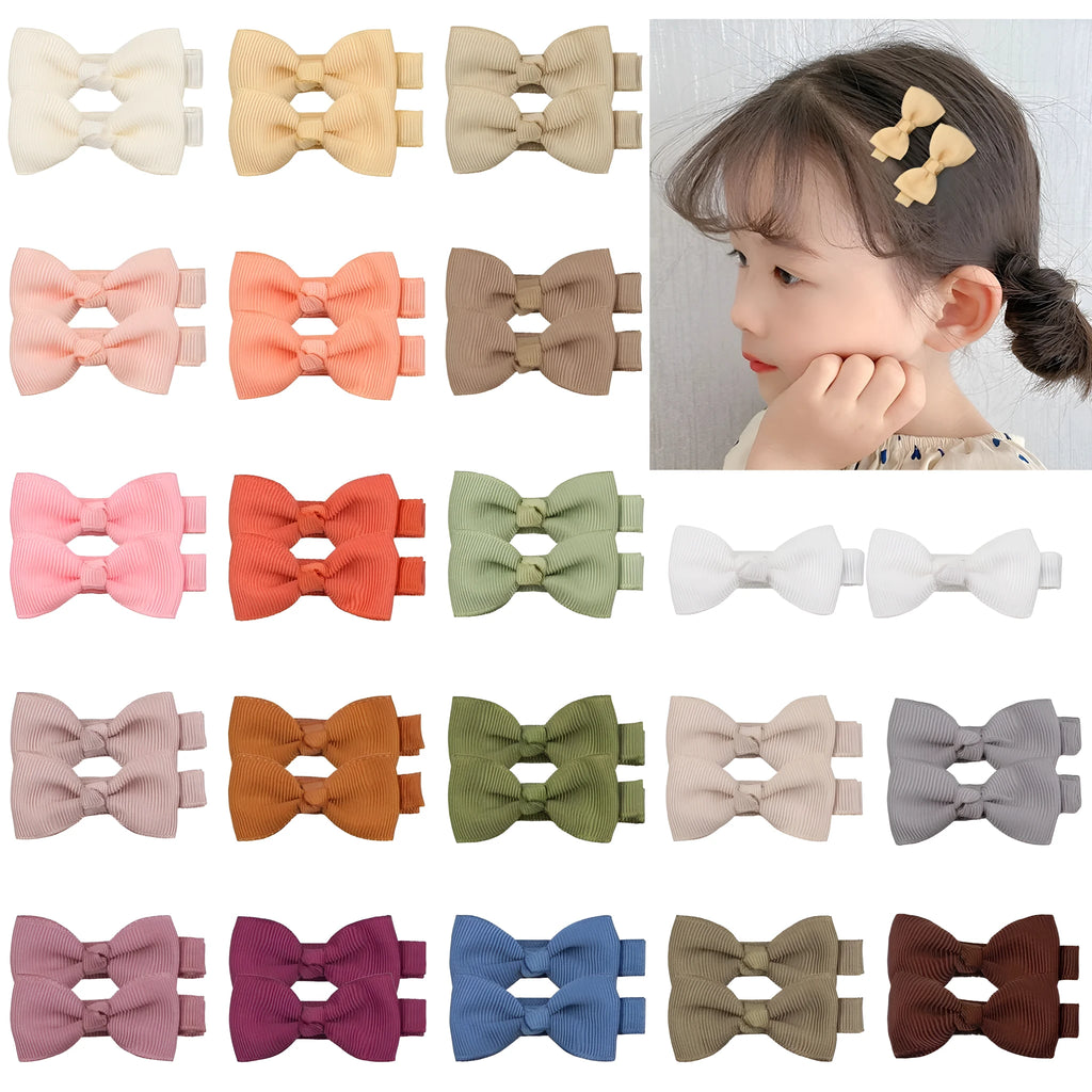 Assortment of pastel-coloured barrette and bow hair clips for babies on a white background.