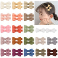 Assortment of pastel-coloured barrette and bow hair clips for babies on a white background.