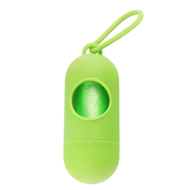 Compact black dog poop bag holder with hook and Velcro strap, shown attached to a pair of trousers.