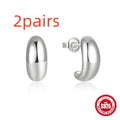 Close-up of a glossy C-shaped sterling silver stud earring with a gold electroplated finish.