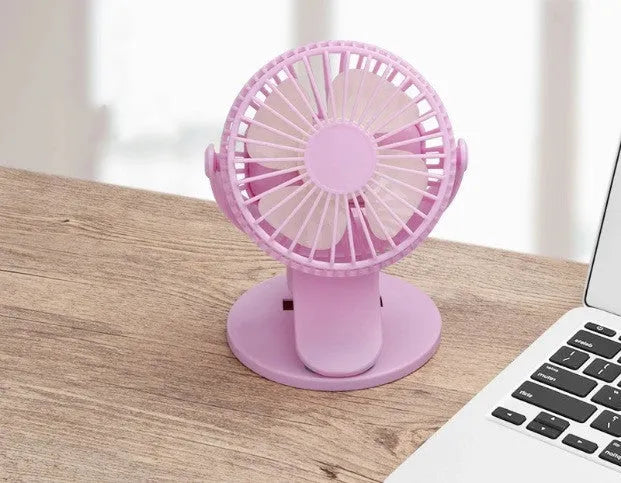 Small white clip fan with USB cable attached to a desk edge