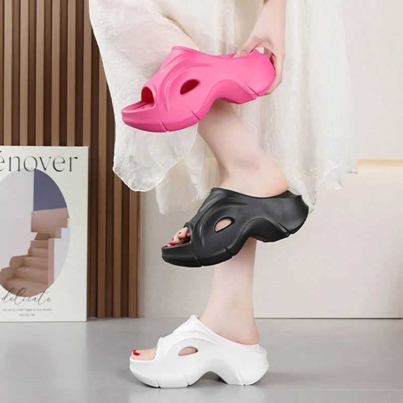 Women's white thick-soled EVA slippers with rounded toe on a sandy beach.