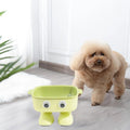 Green robot-shaped elevated cat bowl with tilted food dish and non-slip base.