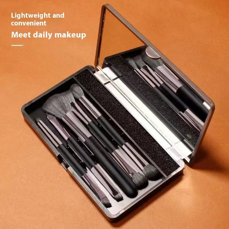 Compact makeup brush set with mirror showing silver or gold finish brushes with artificial fibre heads