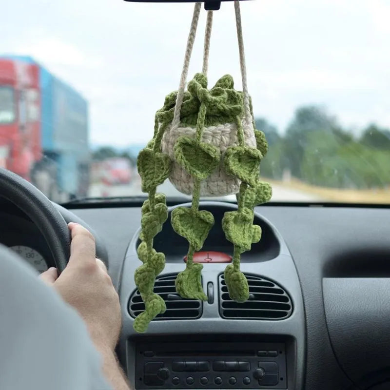 Green and white crochet wool car plant decoration with hanging rope on car dashboard