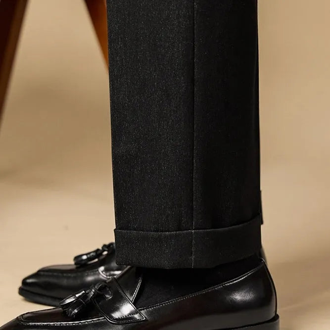 Men's black polished leather tassel loafers on a white background