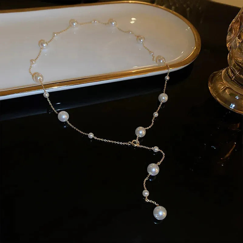 Gold starry pearl choker necklace on a white surface showing imitation pearl chain