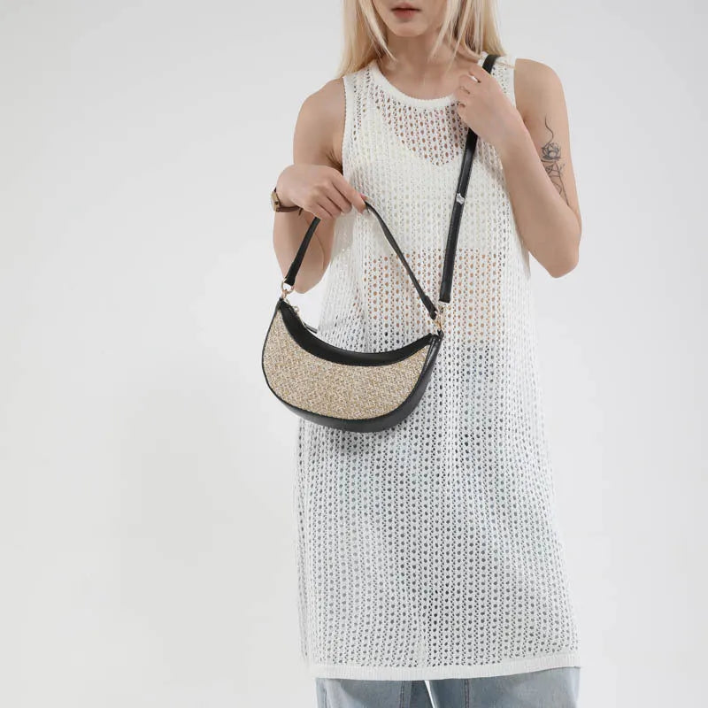 Hard structured straw dumpling shaped women's crossbody shoulder bag in black with contrast stitching.